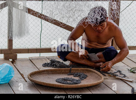 Don Det, Laos - April 24, 2018: Lokale fischer Instandsetzung seiner Metall Angeln equimpent auf einer hölzernen Terrasse in der Nähe des Mekong River Stockfoto