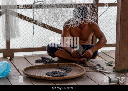 Don Det, Laos - April 24, 2018: Lokale fischer Instandsetzung seiner Metall Angeln equimpent auf einer hölzernen Terrasse in der Nähe des Mekong River Stockfoto