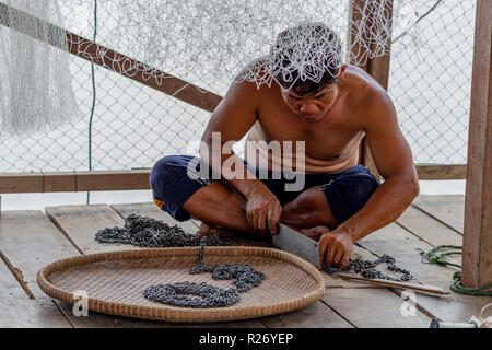 Don Det, Laos - April 24, 2018: Lokale fischer Instandsetzung seiner Metall Angeln equimpent auf einer hölzernen Terrasse in der Nähe des Mekong River Stockfoto