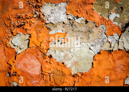 Orange Putz blättert von einer alten Mauer. Alt, dreckig geschält Pflasterwand mit aus fallenden Flocken von Farbe. Textur, Muster, Hintergrund. Stockfoto