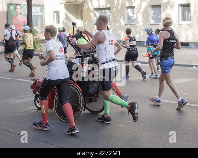 BERLIN, DEUTSCHLAND - 25. SEPTEMBER 2016: Marathon Läufer an Berlin Marathon 2016 laufen in der Innenstadt von Berlin. Man schiebt ein Mann im Rollstuhl. Stockfoto