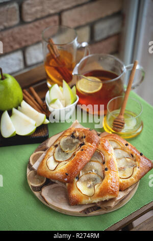 Französische brioche Brötchen mit Birne, Honig und Tee auf hölzernen Tisch Stockfoto