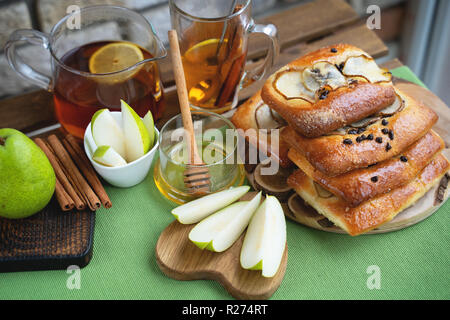 Französische brioche Brötchen mit Birne, Honig und Tee auf hölzernen Tisch Stockfoto