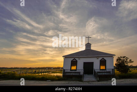 Kleine weiße hölzerne Kapelle auf dem Wasser an der Küste, während ein bunter Sommer Sonnenuntergang Stockfoto