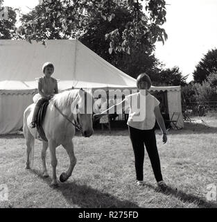 1967, Dorffest, junge Mädchen mit einem Ritt auf einem Pony auf einem Feld außerhalb einer Marke, Oxfordshire, England, UK. Stockfoto