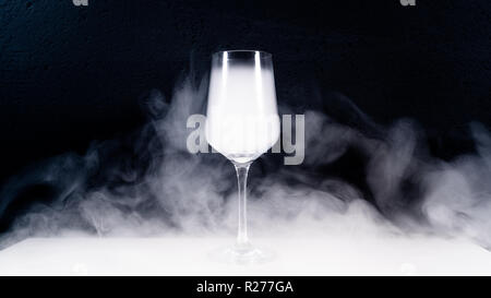 Wein Glas mit Rauch auf einem weißen Tisch gefüllt mit schwarzem Hintergrund, Rauch, Glas, Stockfoto