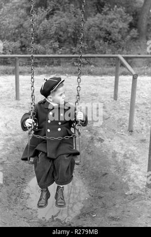 Jungen auf einer Schaukel sitzend in einem Park 1950 Ungarn Stockfoto