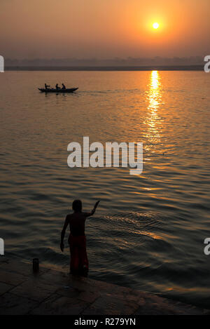 Morgen Ritual und eine Waschmaschine bei Sonnenaufgang an den Ufern des Flusses Ganges in Varanasi, Indien Stockfoto