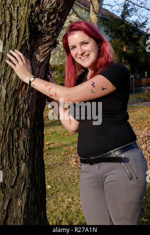 Porträt eines lächelnden jungen Frau mit rot gefärbten Haaren und Fledermäuse auf ihrem Arm lenti Zala Ungarn tätowiert Stockfoto