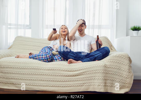 Paar funs mit Flasche Fernsehen sitzen auf einem Sofa im Zimmer Stockfoto