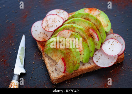 Avocado Toast. Toast Brot mit in Scheiben geschnittenen Avocado, rote Rübe, Sellerie Samen, Paprika. Close Up. Stockfoto