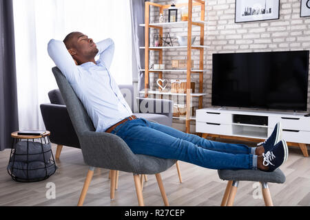 Seitenansicht eines jungen Mann auf Stuhl zu Hause Stockfoto