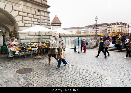 Luzern, LU/Schweiz - vom 9. November 2018: Die vielen geschäftigen Fußgängern und Passanten und Menschen über eine Brücke und einen Marktplatz mit Obst und Gemüse Stockfoto