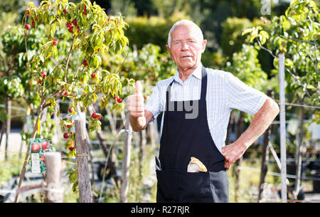 Portrait von zufriedenen älterer Mann seine Lieblingsbeschäftigung der im Garten genießen. Stockfoto