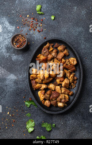 Kolumbianische CHICHARRON. Gebratenes Schweinefleisch chicharron auf schwarzem Teller. Ansicht von oben. Stockfoto