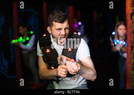 Porträt eines jungen Mannes mit Laser Gewehr Spaß auf dark Laser tag Arena Stockfoto