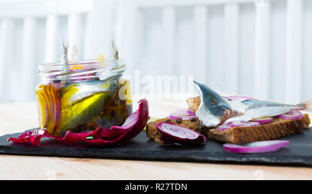 Gebeizt Sprotten in hausgemachten Marinade aus Olivenöl, Essig, Zitronensaft, Meersalz mit Gewürzen, Zwiebeln und Zuckerrüben mit Roggenbrot serviert. Stockfoto