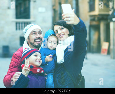 Gerne freundliche Familie mit zwei Kindern zu Fuß die Stadt und tun selfie im Herbst Stockfoto