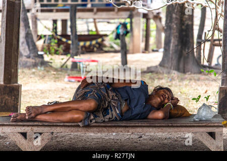 Don Det, Laos - April 24, 2018: ältere Frau auf einer Holzbank in einem Dorf im südlichen Laos schlafen Stockfoto