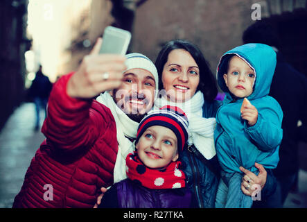 Positive Familie mit zwei Kindern zu Fuß die Stadt und tun selfie im Herbst Stockfoto