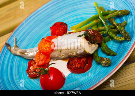 Appetitlich gebackene Blauen Wittling fischen mit getrockneten Tomaten, Spargel und cremige Knoblauchsauce serviert. Stockfoto