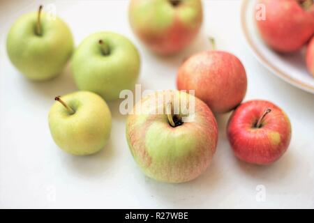 Mehrere ganze Äpfel auf einem weißen Tisch Stockfoto