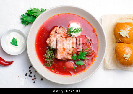 Borscht, rote Suppe aus roten Rüben und Gemüse mit Rippchen und saurer Sahne serviert mit Knoblauch Brötchen, traditionelle Gericht der ukrainischen, Russischen und P Stockfoto
