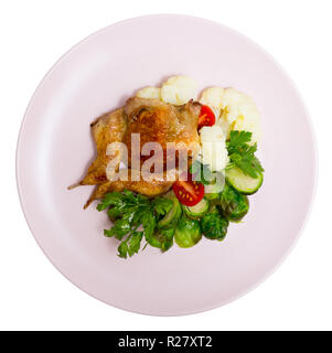 Blick von oben auf die Tabak Wachtel auf Luftkissen gedünsteten Blumenkohl und Rosenkohl, frischen Tomaten und aromatischen Grünen. Auf weissem Hintergrund Stockfoto