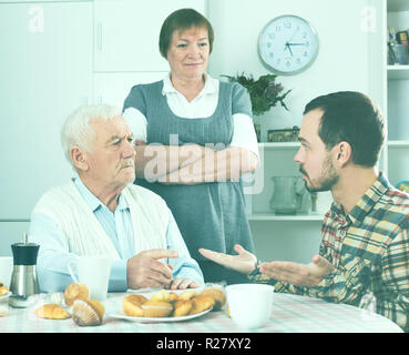 Ältere Großeltern sprechen, ernst und beauftragt Enkel in Anwesenheit von Großmutter Stockfoto