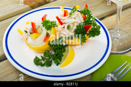 Tropischer Salat mit Calamari, Gurken, rote Paprika, in Zitrone Hälften mit Olivenöl und griechischer Joghurt serviert. Stockfoto
