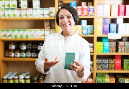 Portrait von fröhlichen reife weibliche Apotheker mit biologisch aktive Nahrungsergänzungsmittel Paket Stockfoto