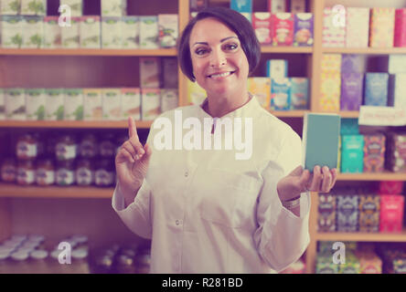 Lächelnd reife Frau Verkäufer halten Nährstoffe in der Ernährung gesund Apotheke Stockfoto