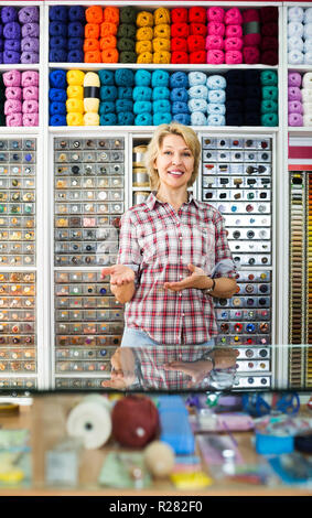 Portrait von Reifen gerne weibliche Kassierer an der Kasse in der Stickerei Shop Stockfoto