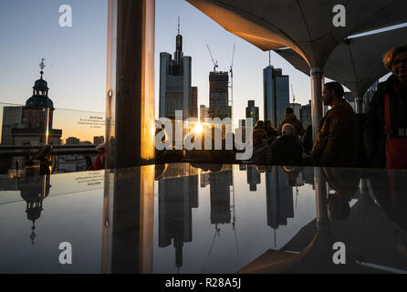 17. November 2018, Hessen, Frankfurt am Main: Frankfurter Skyline mit seiner Bank Towers ist im Abendlicht in einem Glas Oberfläche auf der Dachterrasse ein Restaurant im Zentrum der Stadt wider. Foto: Frank Rumpenhorst/dpa Stockfoto