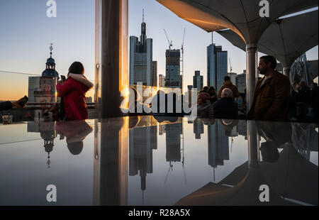 17. November 2018, Hessen, Frankfurt am Main: Frankfurter Skyline mit seiner Bank Towers ist im Abendlicht in einem Glas Oberfläche auf der Dachterrasse ein Restaurant im Zentrum der Stadt wider. Foto: Frank Rumpenhorst/dpa Stockfoto