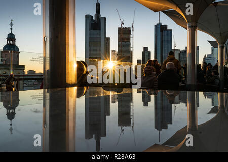 17. November 2018, Hessen, Frankfurt am Main: Frankfurter Skyline mit seiner Bank Towers ist im Abendlicht in einem Glas Oberfläche auf der Dachterrasse ein Restaurant im Zentrum der Stadt wider. Foto: Frank Rumpenhorst/dpa Stockfoto