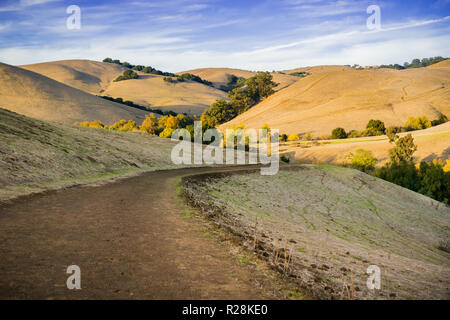 Wanderweg durch goldene Berge bei Sonnenuntergang in Garin Dry Creek Pioneer Regional Park, östlich der Bucht von San Francisco, Kalifornien Stockfoto