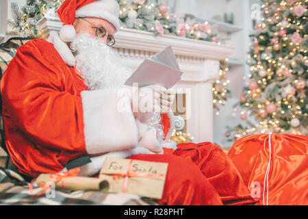 Bild von Santa Claus sitzen und lesen. Er hält sie in den Händen. Man ist konzentriert und ernst. Stockfoto