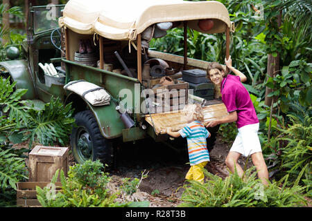 Mann und Kind push Auto im Schlamm im Dschungel fest. Familie drücken off road Fahrzeug im Schlamm Schmutz Gelände in tropischen Wald stecken geblieben. Insel Adventure Drive. Stockfoto