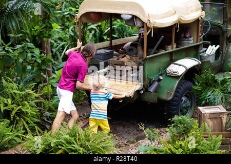 Mann und Kind push Auto im Schlamm im Dschungel fest. Familie drücken off road Fahrzeug im Schlamm Schmutz Gelände in tropischen Wald stecken geblieben. Insel Adventure Drive. Stockfoto