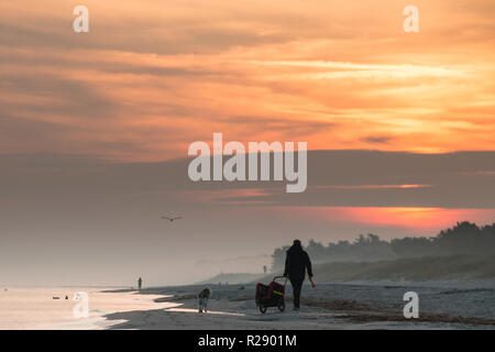 Prerow, Deutschland - Oktober 10, 2018: Ein Mann, der seinen Hund während der Sonne entlang der Ostsee, Deutschland steigt. Stockfoto