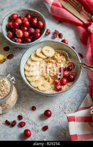 Keramische Schüssel Haferflocken Haferflocken mit Banane, frische Preiselbeeren und Walnüsse Stockfoto