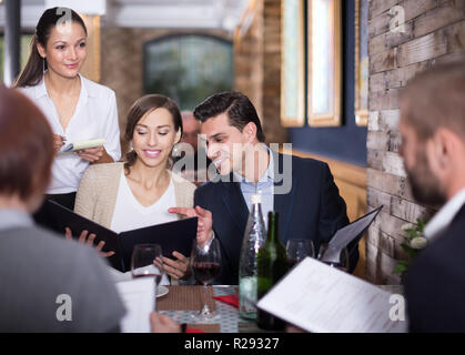 Mitarbeiter Kellnerin Frau, um von positiven Besucher im Restaurant Stockfoto