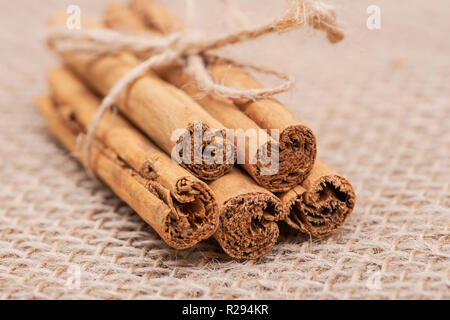 Cinnamon Sticks mit Jute Seil auf sackleinen Hintergrund gebunden Stockfoto