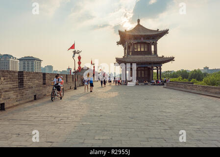 Xi'an, Provinz Shaanxi, China - Aug 8, 2018: die Menschen Wandern und Reiten Fahrrad auf die Stadt befestigten Mauer am späten Nachmittag Stockfoto