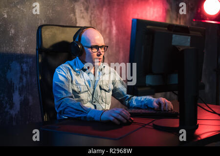 Ernsthaften jungen Mann sitzen und arbeiten mit Computer im dunklen Büro. Stockfoto