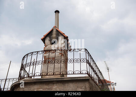 Alte Kamin aus roten Backsteinen auf einem Dach mit blauem Himmel und weißen Wolken im Hintergrund. Großen Schornstein. Außen Details. Stockfoto