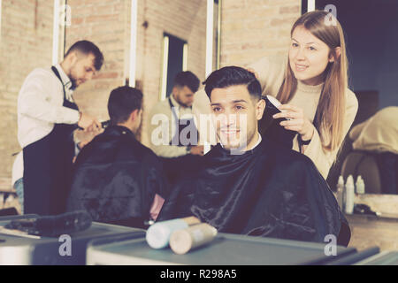 Professionelle friseur Frau tun Styling hübscher Kerl mit elektrischer Haarschneider bei Friseur Stockfoto