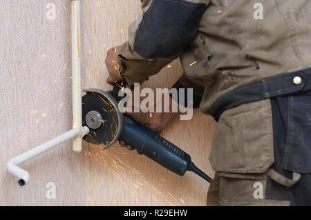 Der Klempner schneidet das Metallrohr mit einem Winkelschleifer. Spray von Funken. Stockfoto