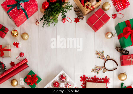 Weihnachten noch leben. Geschenke, Dekorationen, Geschenkpapier und Ornamente auf Holzboden. Ansicht von oben mit der Kopie. Stockfoto